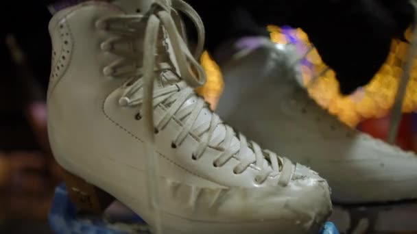 バックグラウンドで2番目のぼやけた靴のレースを結ぶ女性の手でクローズアップ白いアイススケート 閉鎖認識できない若いです女性取得準備のためにスケート屋外 — ストック動画