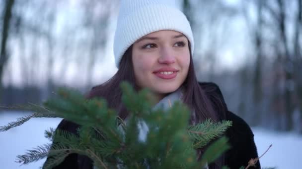 年轻女子心满意足 绿松林枝头环视四周 笑着站在冬季的森林里 积极乐观的高加索游客在早晨享受周末闲暇的画像 — 图库视频影像
