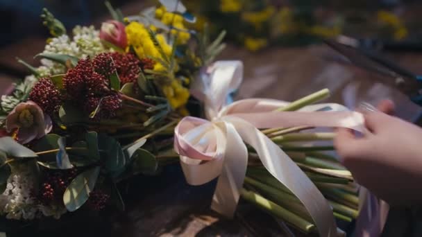 雌性白种人的手在室内切粉红缎带 在花朵上鞠躬 在花店里做花束卖的不为人知的有才华的年轻女人 — 图库视频影像