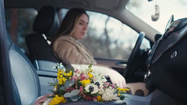 乘客座位上的一束鲜花 戴着太阳镜 模糊的年轻女子坐在司机座位上 持情人节礼物乘坐汽车的白人女士侧观 — 图库视频影像