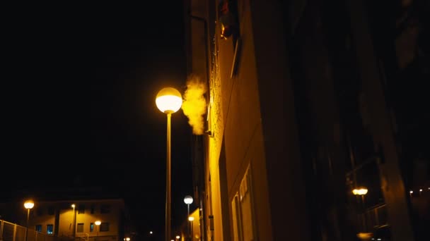 街の黄色い街灯のパイプから 白い蒸気が出てくる 屋外の暗闇の中の夜の街 — ストック動画