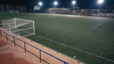 İspanya 'da geniş açılı boş gece stadyumu. Karanlıkta yeşil atletizm sahasında kimse yok.