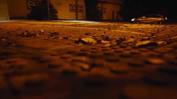 クローズアップアスファルト道路 車が通過し 女性の足が夜に通りを横断する 黄色の都市ライトで暗闇を散策する認識できない女性を閉じる — ストック動画