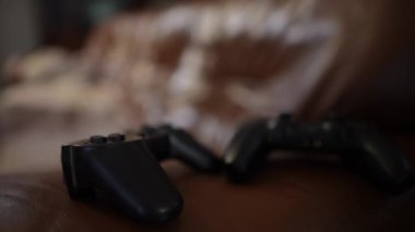 Kanepede iki joystick 'i yavaşça kanepede oturup oyun kumandalarını alan bulanık adamlarla yakın çekim. Tanınmaz haldeki Kafkas dostları hafta sonları oturma odasında oyun oynuyorlar.