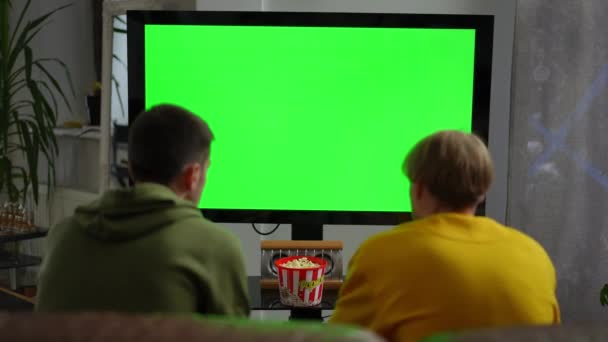 Shooting Shoulder Two Young Men Watching Green Screen Plasma Monitor — Stok Video