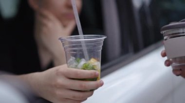 Erkek eli plastik bardakta içki içerken kadın avuç içi cam ile yaklaşıyor. Tanımlanamayan Kafkasyalı genç bir kadın smoothie için erkeklere daha iyi bir seçenek sunuyor.