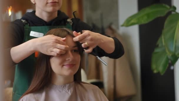 Refleksja Lustrze Zadowolonej Kobiety Siedzącej Salonie Piękności Jako Nierozpoznawalny Fryzjer — Wideo stockowe