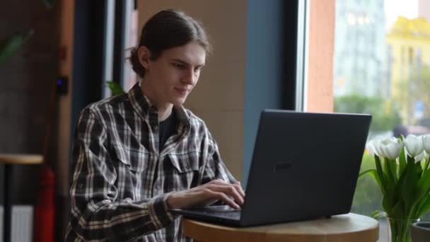 Junger Mann Lächelnd Tippt Auf Laptop Tastatur Und Sitzt Tisch — Stockvideo