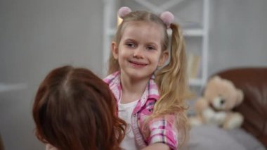 İki örgülü, gülümseyen sarışın kızın portresi. Tanımlanamayan bir kadının gülümsemesi. Çekici beyaz kız annesini kucaklıyor ve evde ailesiyle vakit geçiriyor.