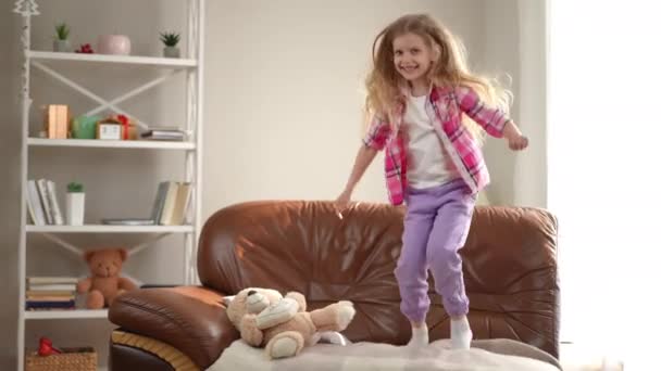 Wide Shot Cheerful Laughing Little Girl Jumping Couch Living Room — Stock Video