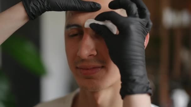 Крупным Планом Лицо Молодого Человека Руками Косметолога Вытирающего Пену Бровей — стоковое видео