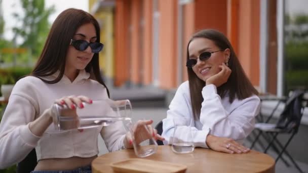 Okouzlující Usměvavé Ženy Mluví Nalévání Vody Brýlích Sedící Stolu Kavárně — Stock video