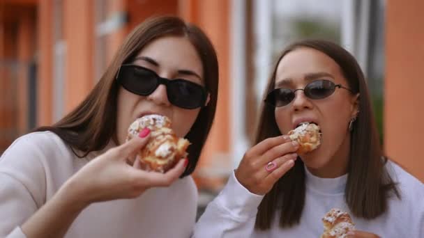 Two Young Women Sunglasses Biting Chewing Delicious Croissants Looking Camera — Stock Video