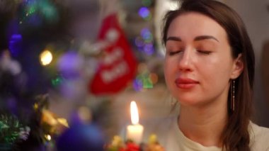 Ağır çekim. Bir dilek tutmuş güzel bir kadının Noel mumunun alevini söndüren görüntüsü. Sihirli Noel gecesi