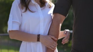 Ağır çekim. Bir kadının, bir erkeğin eline sarıldığı yakın plan. Birbirine aşık bir çift, bir adam ve bir kadın bahar parkında