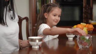 Bir çocuğun tatlı mutluluğu. Masada annesiyle oturan mutlu bir kız bir şeker alır ve kameraya gösterir.
