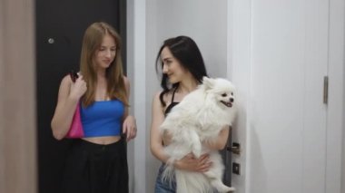 Dairenin sahibi, kollarında bir köpekle, kapıda arkadaşıyla karşılaştı ve onu daireye götürdü.