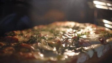 Sebze ve peynirli et güveci, roka yapraklarıyla süslenmiş, fırında cam bir kabın içinde. Yakın plan.