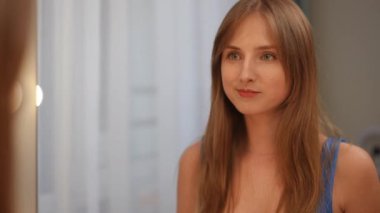 Kız aynada kendine bakıyor. Kızın keyfi yerinde, kendine gülümsüyor, öpücükler yolluyor, saçını düzeltiyor.