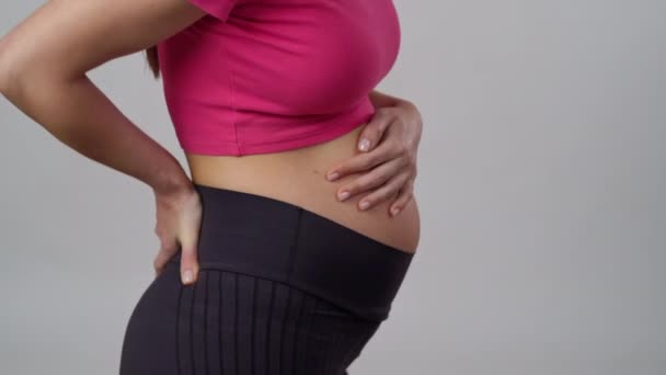 无法辨认的孕妇站在白色的背景上 用手按摩背 — 图库视频影像