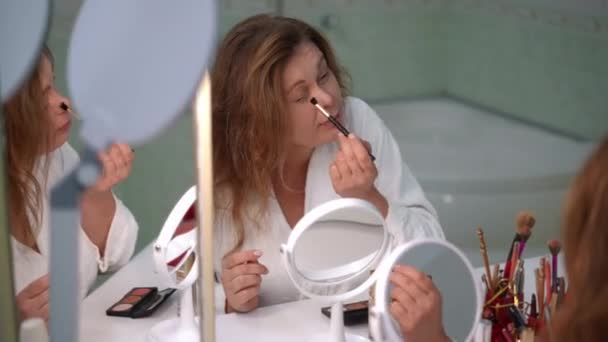 Μια Γυναίκα Λευκό Μπουρνούζι Κάνει Ένα Γρήγορο Πρωινό Μακιγιάζ Ενώ — Αρχείο Βίντεο