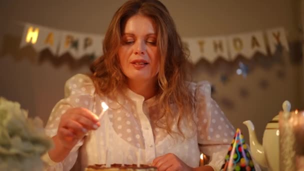 Ευτυχισμένη Γυναίκα Ανάβει Κεριά Μια Τούρτα Γενεθλίων Ενώ Κάθεται Στο — Αρχείο Βίντεο