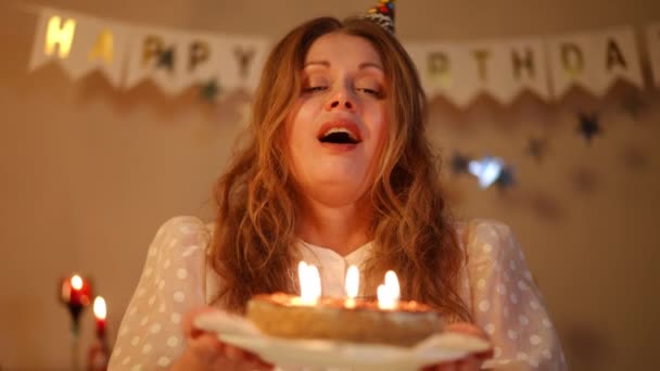 Eine Frau Mit Geburtstagskappe Hält Eine Geburtstagstorte Mit Brennenden Kerzen — Stockvideo