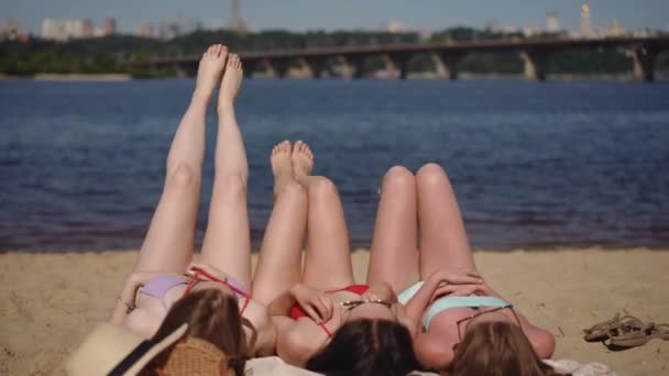 Τρία Κορίτσια Μαγιό Ξαπλώνουν Στην Πλάτη Τους Μια Αμμώδη Παραλία — Αρχείο Βίντεο