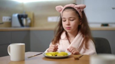 Bornozlu bir çocuk lezzetli bir kahvaltı beklentisiyle ellerini ovuşturur, üzerinde iki dolu krep olan bir tabağın olduğu bir masaya oturur. Küçük kız bir çatal ve bıçak aldı ve...