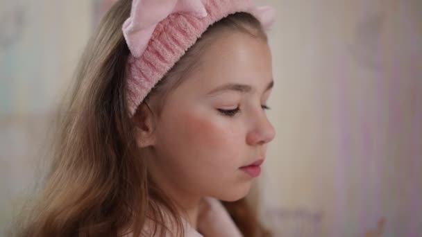 クローズアップ スローモーション 彼女の頭に猫の耳が付いているピンクの化粧品のヘアバンドが付いている少女は 彼女の頬に粉のブラシが付いている粉を加えます 自宅でメイクをしている女の子 — ストック動画