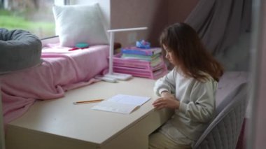 Kız üzüldü ve egzersiz defterine yazmak için kullandığı kalemi attı. Çocuk, kollarını göğsünün üzerinde çaprazlayarak sandalyesine yaslandı.