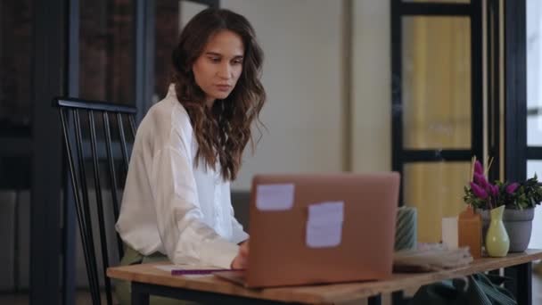 トレンディなモダンなオフィスでデスクに座っている間 ノートパソコンで働くビジネス女性 女性はラップトップを見て鉛筆で書いています テーブルの上の香りのする臭いキャンドルスモーク — ストック動画
