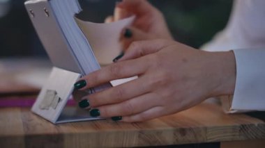 Ağır çekim. Yakın plan. Bir kadının elleri yırtık bir takvime çarşaf geçirir, buruşturur ve masaya fırlatır.