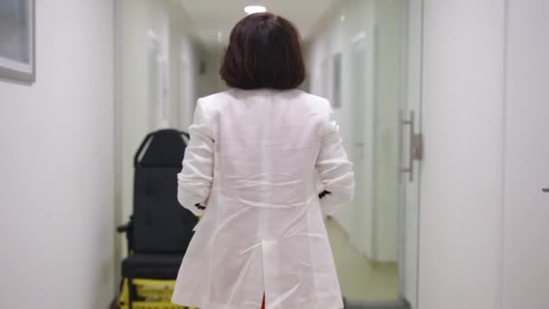 Rear View Female Doctor White Jacket Walks Hospital Corridor Stops Videoclip de stoc