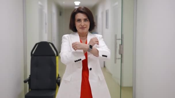 Hospital Corridor Woman White Jacket Stands Looks Camera Smile Crossing Secvență video de stoc fără drepturi de autor