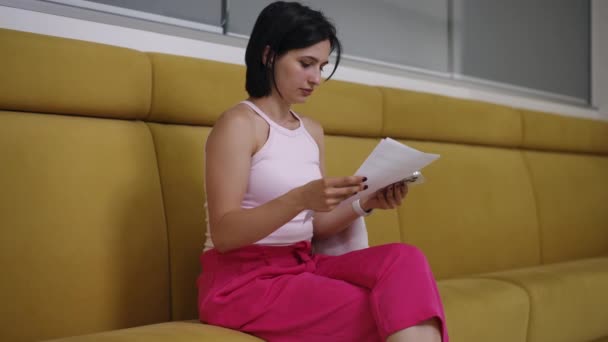 Woman Seen Seated Yellow Couch Attentively Looking Piece Paper Her Clip video
