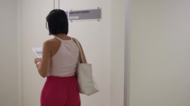 Woman Approaches Gynecologists Office Paper Her Hand Looks Sign Wall Videoclip de stoc fără drepturi de autor