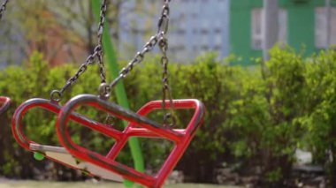 Yakın plan. Boş metal salıncak koltukları güneşli bir bahar gününde açık havada metal zincirlerde sallanıyor.