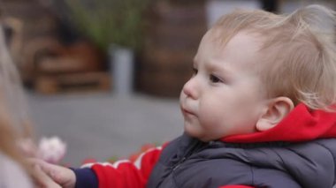 Ağır çekim. Yakın plan. Küçük bir çocuk güzel kokar, çiçek açan laleler bir bahar günü şehir merkezindeki bir çiçek fuarında dikilirken