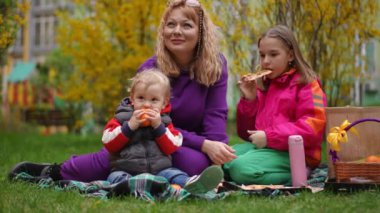 Ağır çekim. Baharda şehir parkında çimlerin üzerinde aile pikniği. Anne gülümsüyor, genç kızı pizza yiyor ve küçük oğlu soyulmamış bir mandalinayı kemiriyor.