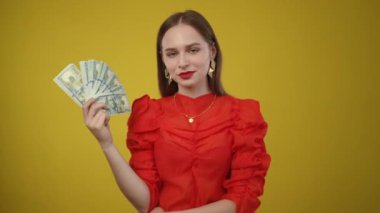 Canlı bir ortamda, şık genç bir kadın başarısını ve başarılarını vurgulayarak, güvenle parasıyla hava atıyor.
