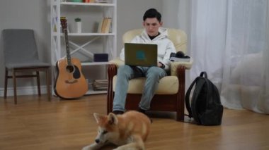 Sıcak bir evde, genç bir adam dizüstü bilgisayarıyla çalışır. Sadık köpeği ona arkadaşlık eder, sıcak bir ortam yaratır.
