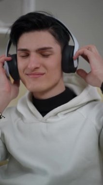 Neşeli bir genç, müzik dinlerken kablosuz kulaklıkla gülümsüyor.