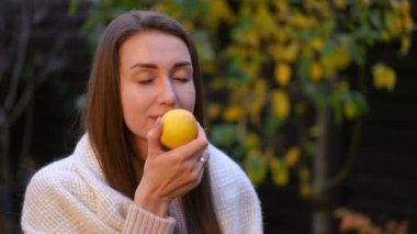 Huzurlu bir kadın, parlak bir limonla keyifli bir anın tadını çıkarıyor, yemyeşil ve doğal ortamında.