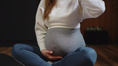 Huzurlu hamile bir kadın bir bardak su tutuyor, bu sakin zamanda susuzluk ve kendine bakım vurguluyor.