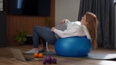 Bir kadın, evindeki modern yaşam alanında canlı bir mavi egzersiz topunda dinlenirken eğlenir.