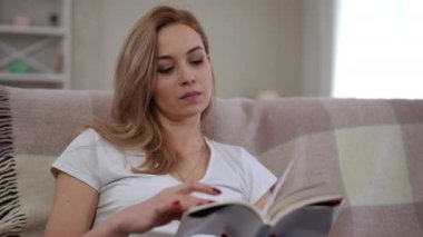 Huzurlu bir kadın sıcak bir evde büyüleyici bir kitap okumanın zevkini çıkartıyor.