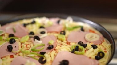 Lezzetli jambon, zeytin ve taze taze soğanla kaplı ağız sulandıran bir pizza, mükemmelliğe hazır.