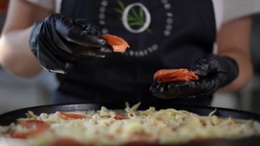 Uzman eller taze pizzaya çeşitli malzemeler ekliyor. Mutfak sanatını ve her ayrıntıyı gözler önüne seriyor.