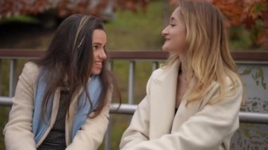 İki arkadaşın güzel sonbahar manzarasının ortasında neşeli ve unutulmaz bir anı paylaştığı yakın çekim görüntüsü.